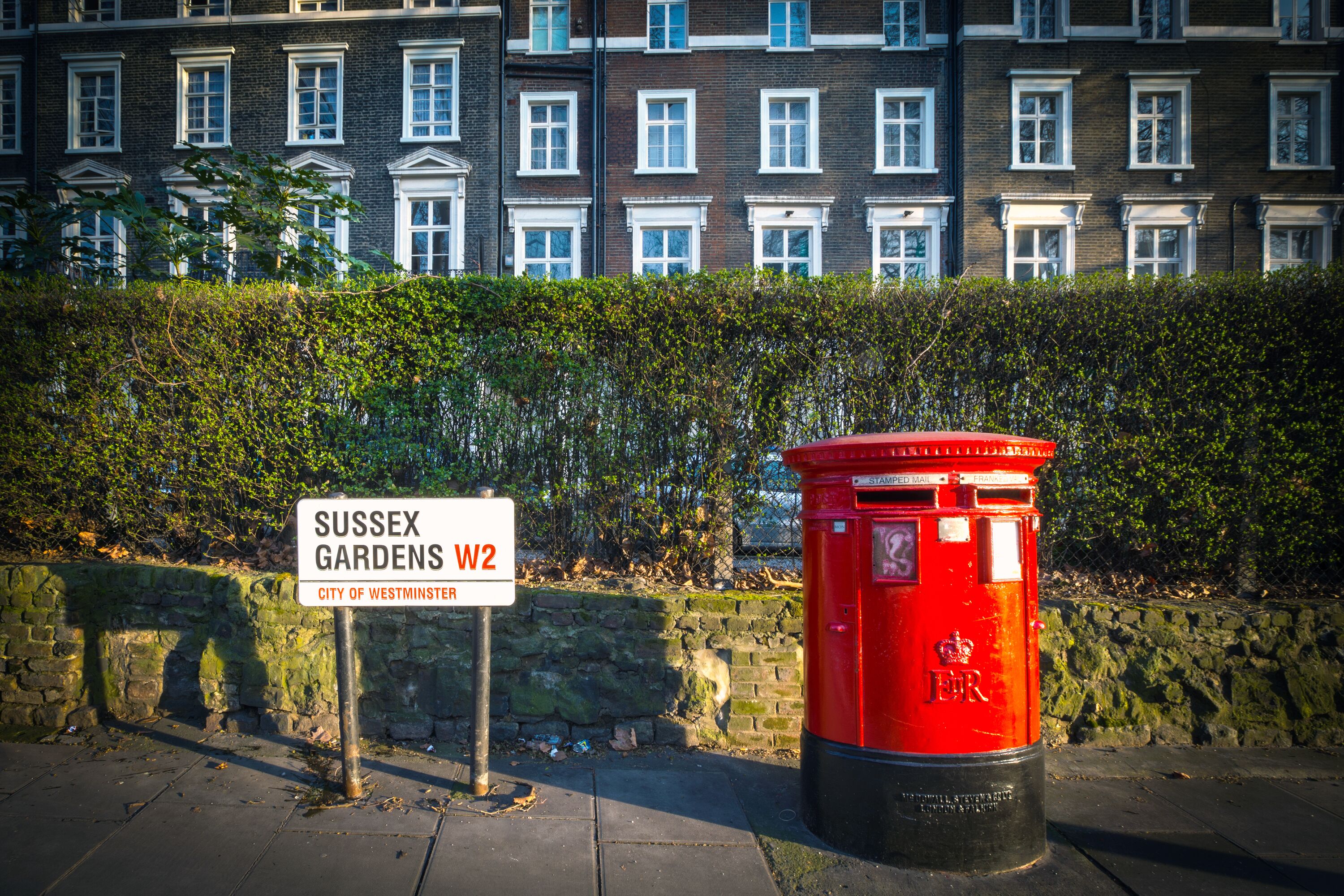 A red post box and a sign indicating Sussex Gardens, W2, City of Westminster.