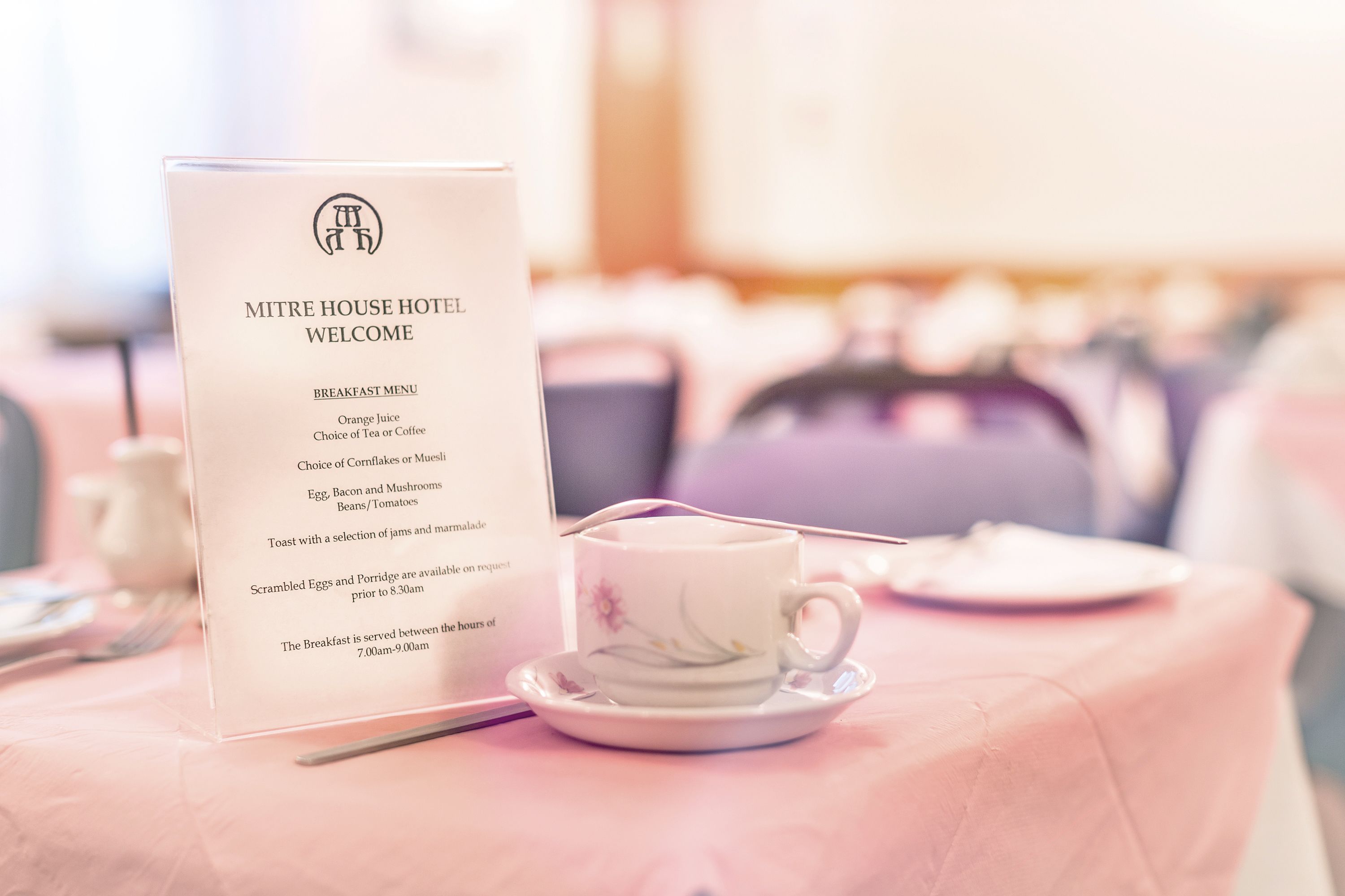 A breakfast menu at the Mitre House Hotel with a floral cup and saucer on a pink tablecloth.