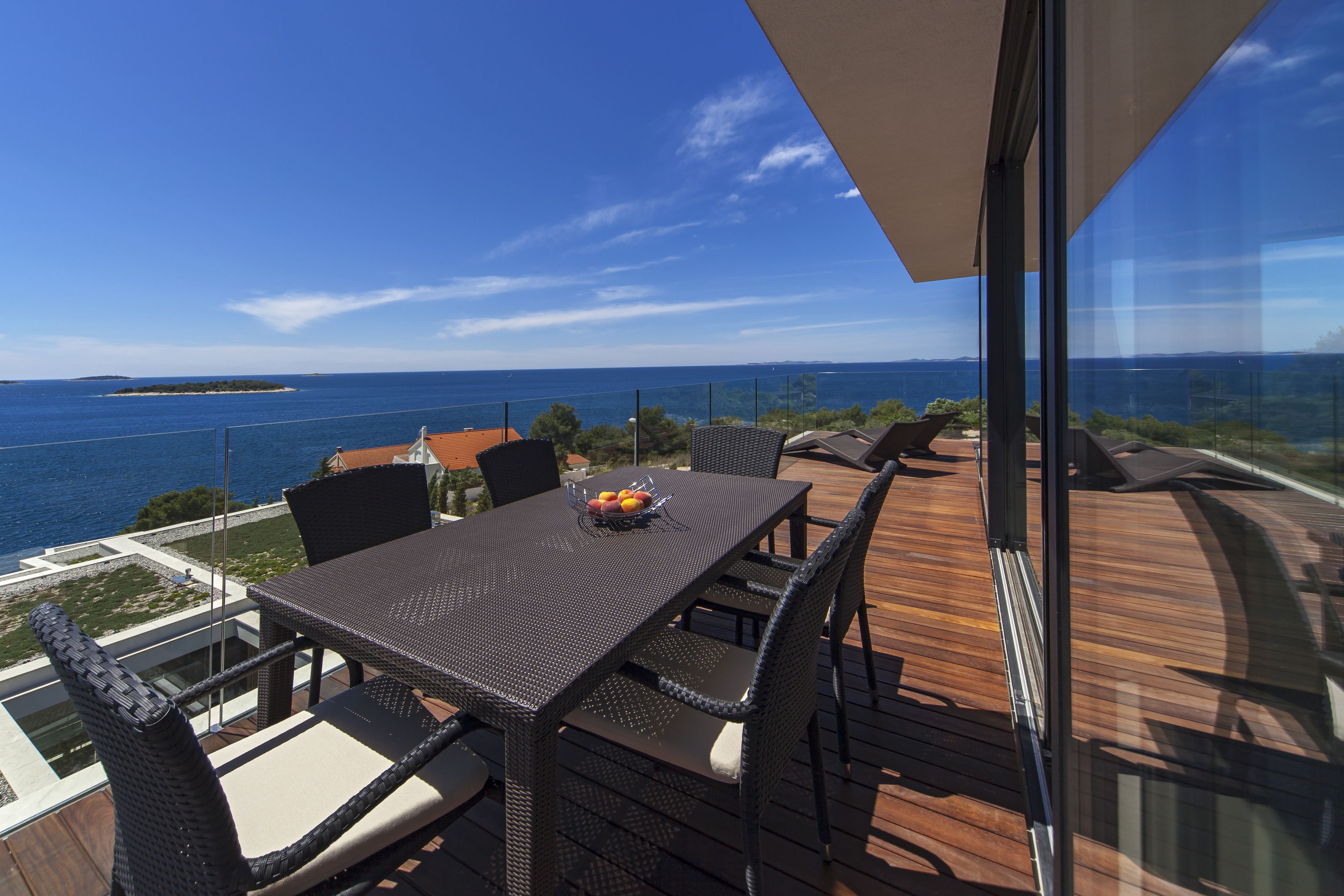 A deck with a table and chairs overlooking a body of water.
