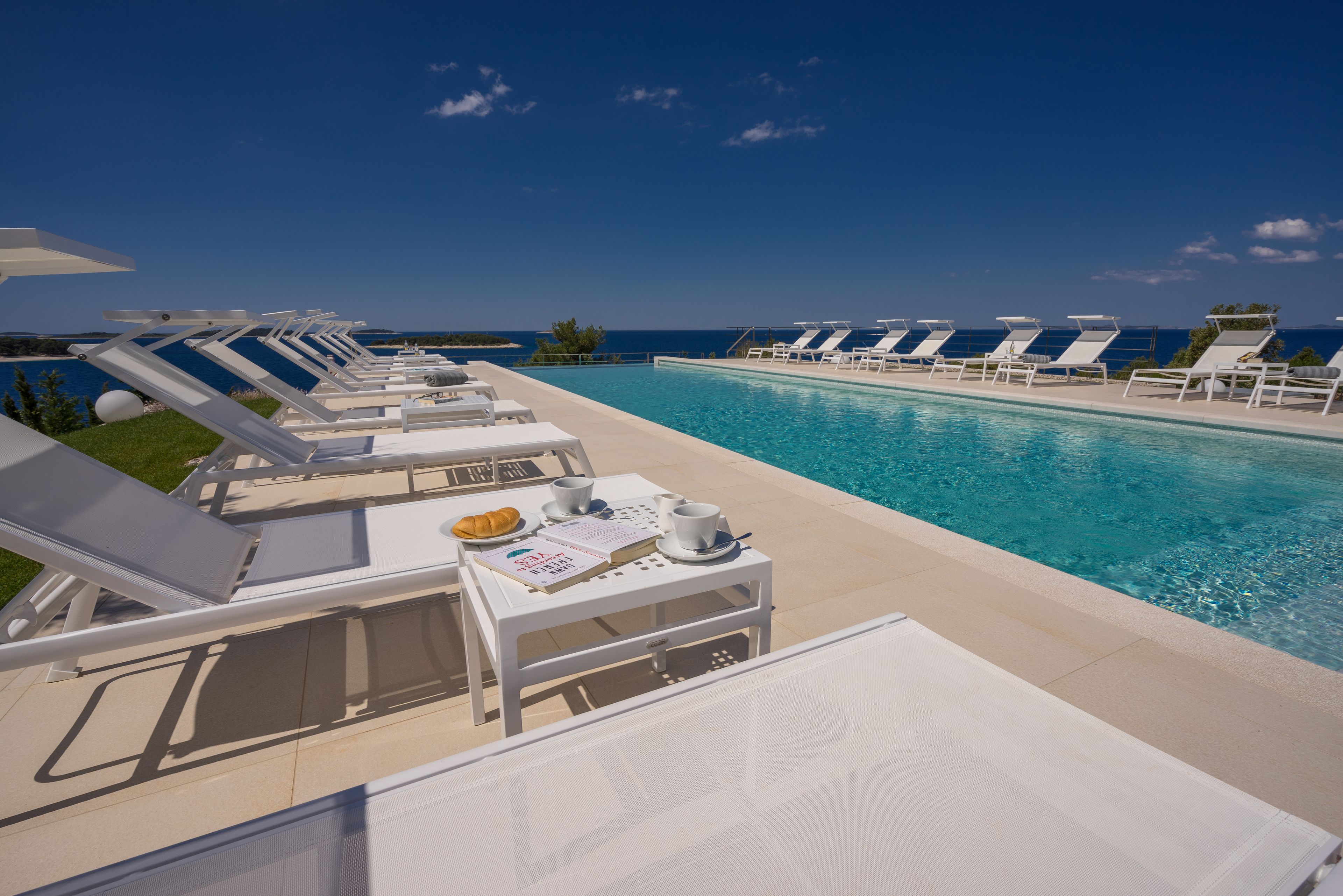 Zona de piscina con tumbonas y una mesa con un menú y un croissant.