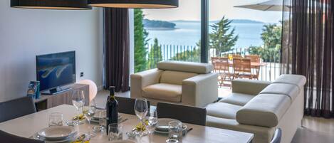 A dining area with a table set for four, a sofa, and a view of the sea.