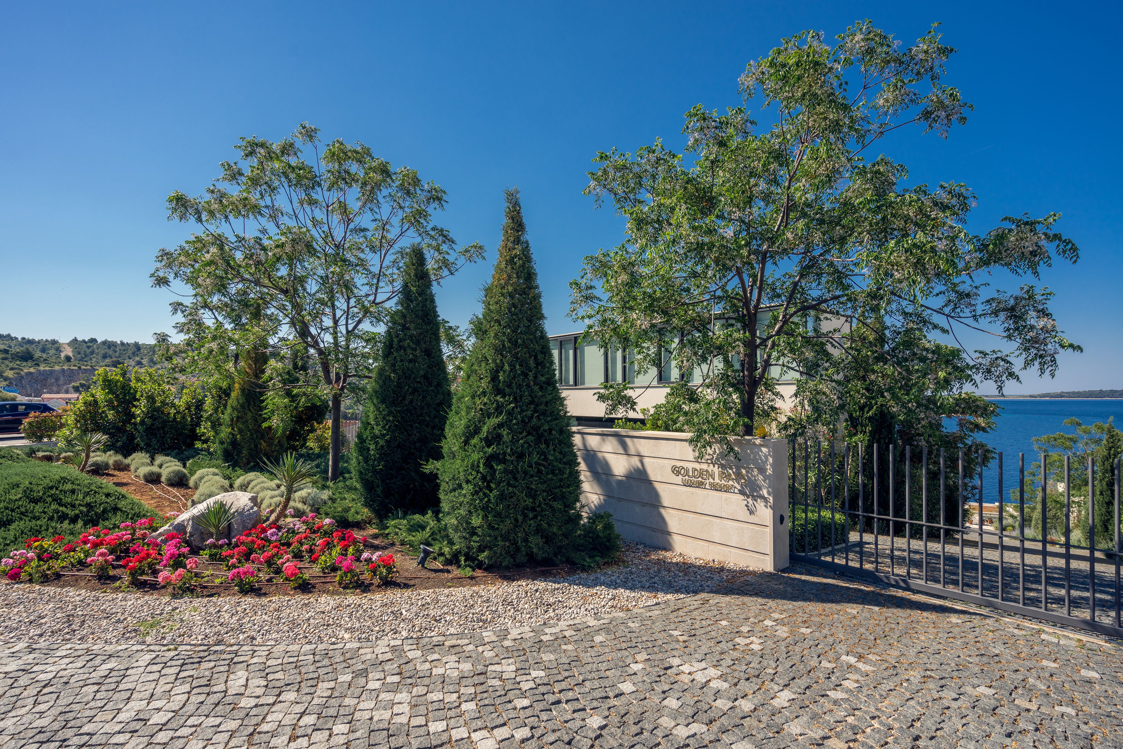 Ein Kopfsteinpflasterweg führt zu einem Gebäude mit der Aufschrift 'Golden Bay Luxury Resort'.