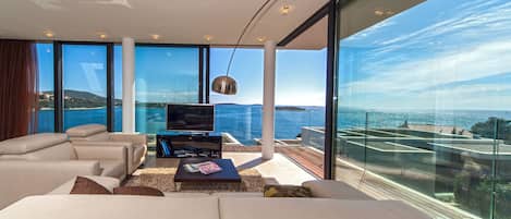Una sala de estar moderna con un televisor grande, asientos cómodos y vistas al mar.