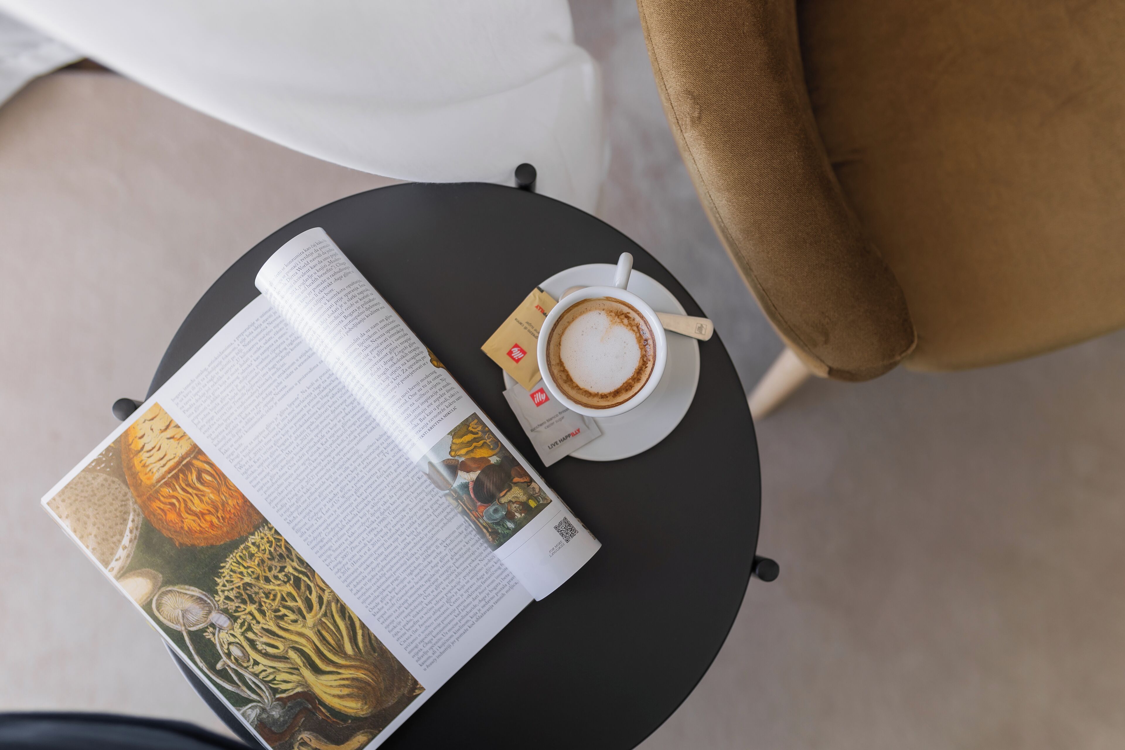 Un libro, una taza de café y un menú sobre una mesa redonda.