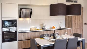Una cocina moderna con electrodomésticos integrados, un comedor con una mesa dispuesta para dos personas y un amplio ventanal que proporciona luz natural.