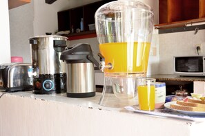 A kitchen counter with a coffee maker, a blender, a toaster, and a plate with toast and jam. - El Viajero Asuncion Hostel & Suites (Asunción)