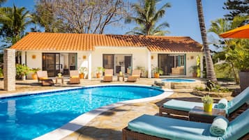 Relax by the pool surrounded by lush greenery and palm trees.