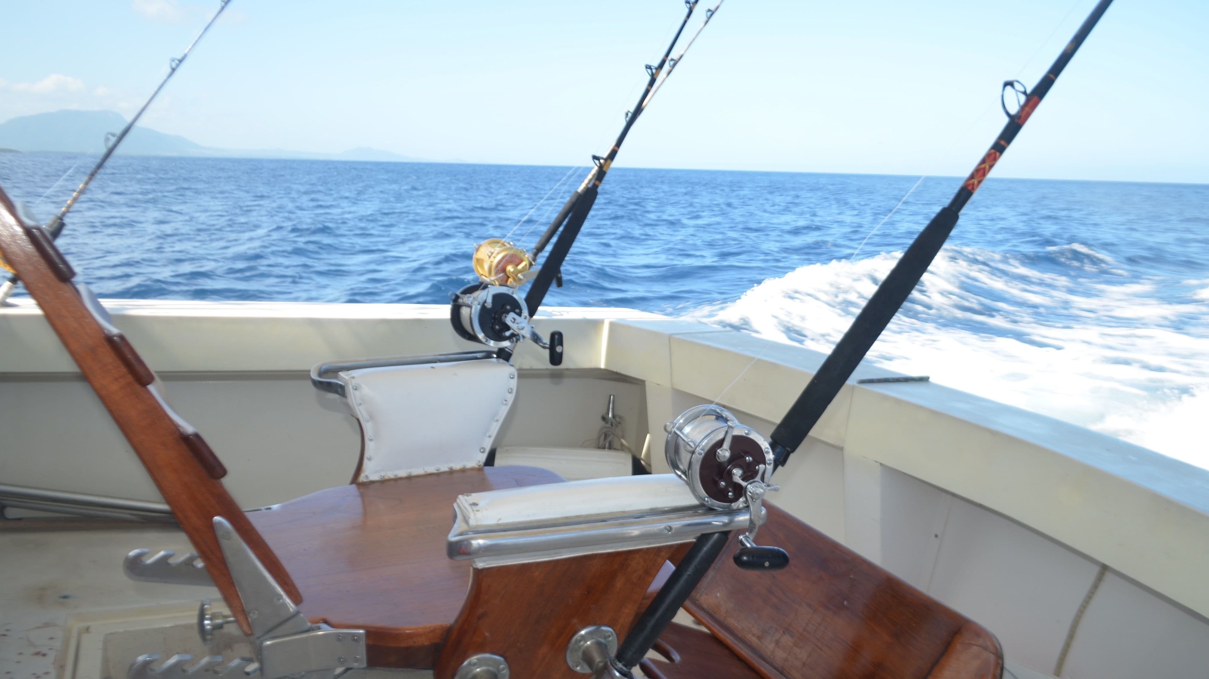 A boat's interior with fishing rods and a view of the ocean.