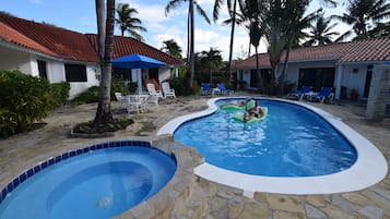 Una piscina al aire libre, sombrillas, sillones reclinables de piscina