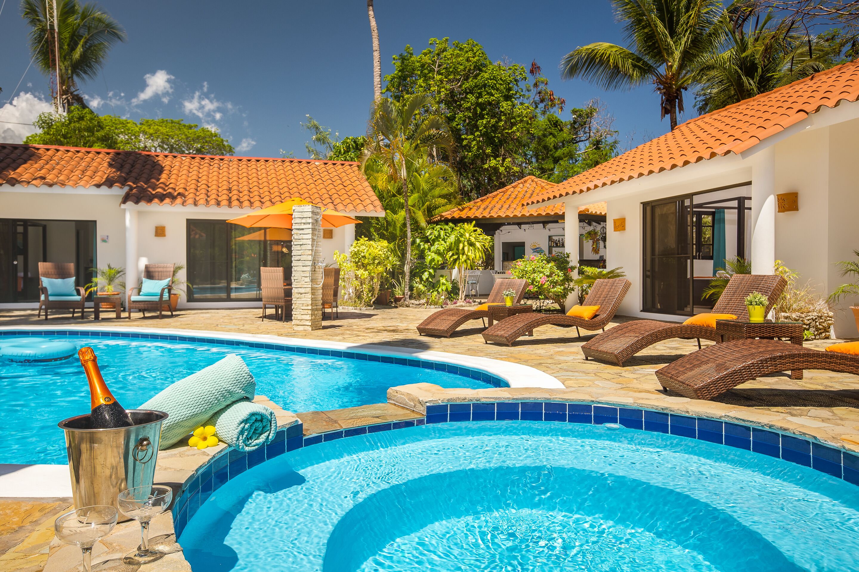 A swimming pool area with lounge chairs, a bottle of champagne, and a glass.