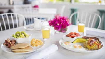 A breakfast table with various dishes including pancakes, eggs, and fruit.