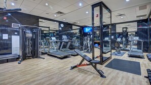 Un gimnasio con cintas de correr, elípticas y equipo de levantamiento de pesas.