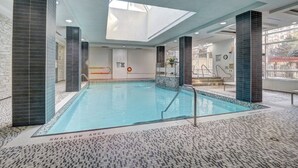 Una piscina interior con paredes y suelo de baldosas, y un tragaluz arriba.