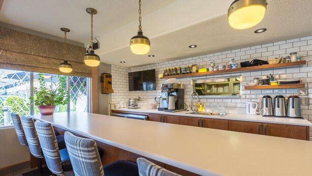 A modern kitchen with a large island, bar stools, and pendant lighting. - Grama's Inn (Prince George)