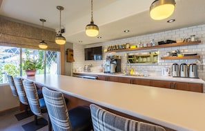 Una cocina moderna con una isla grande, taburetes de bar e iluminación colgante.
