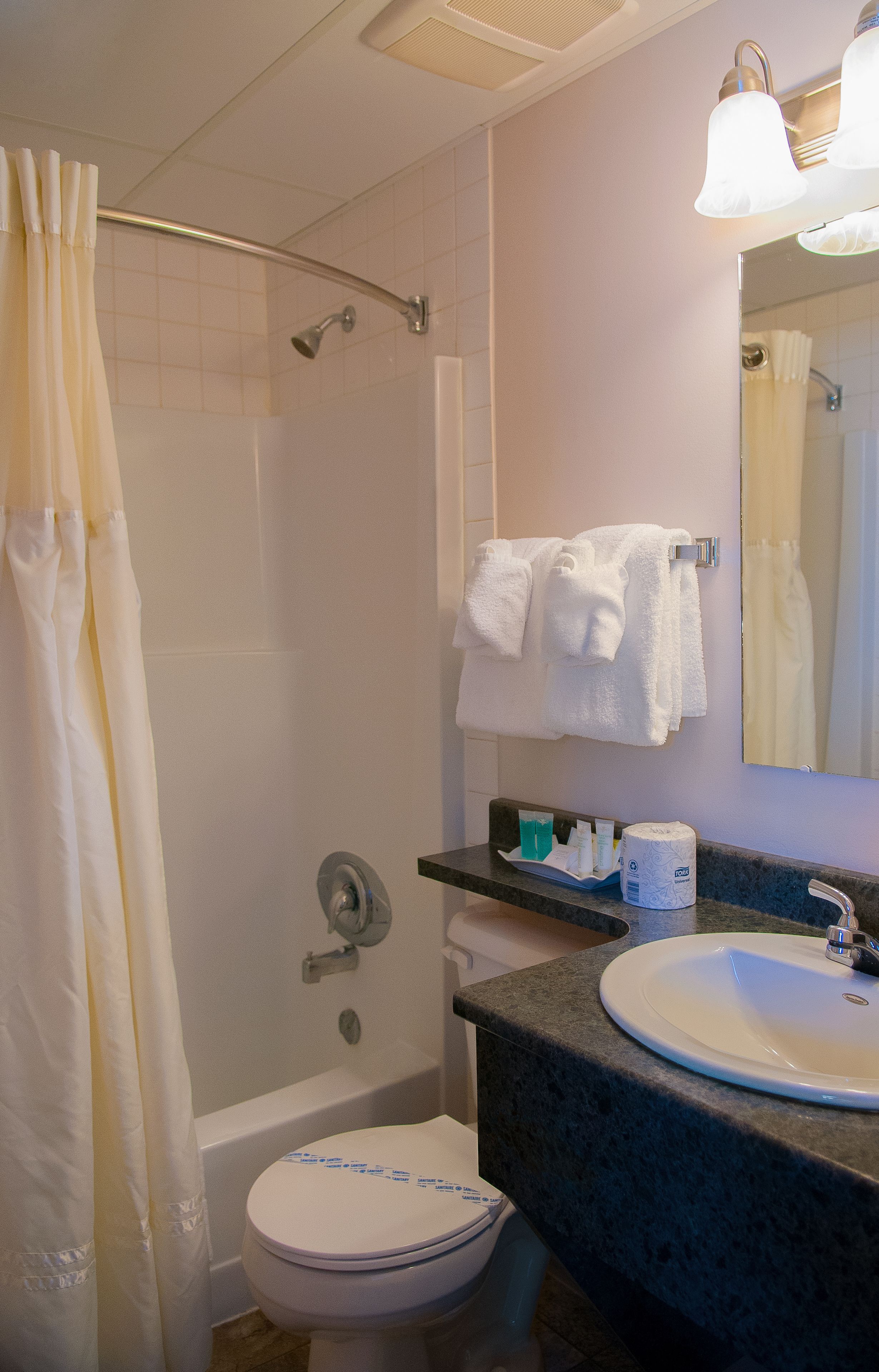Un baño con ducha, inodoro, lavamanos y toallero.