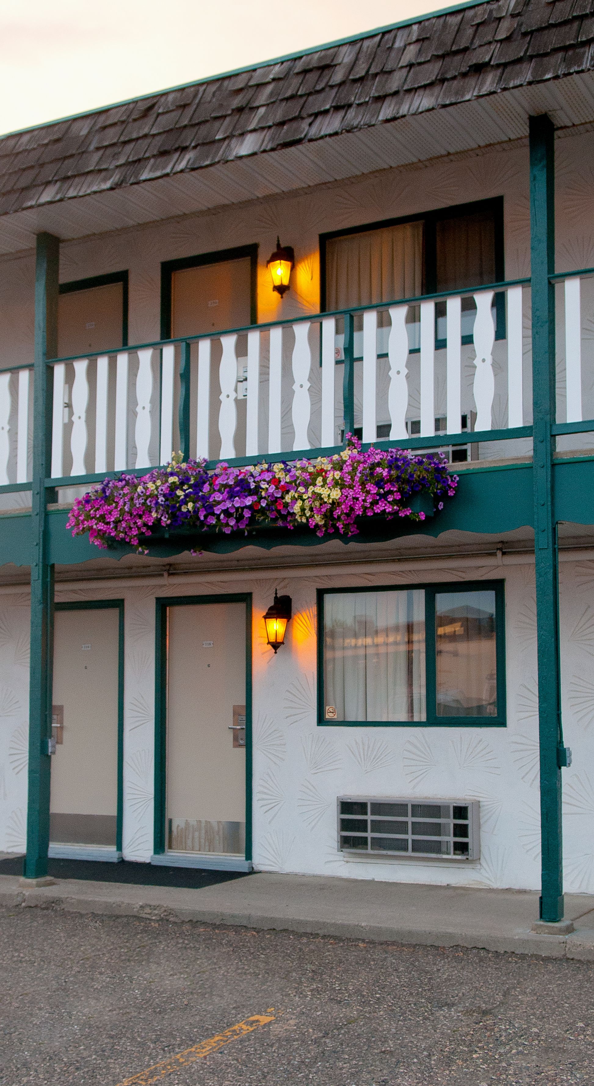 Un edificio de dos pisos con balcón, jardineras y una puerta con ventana.