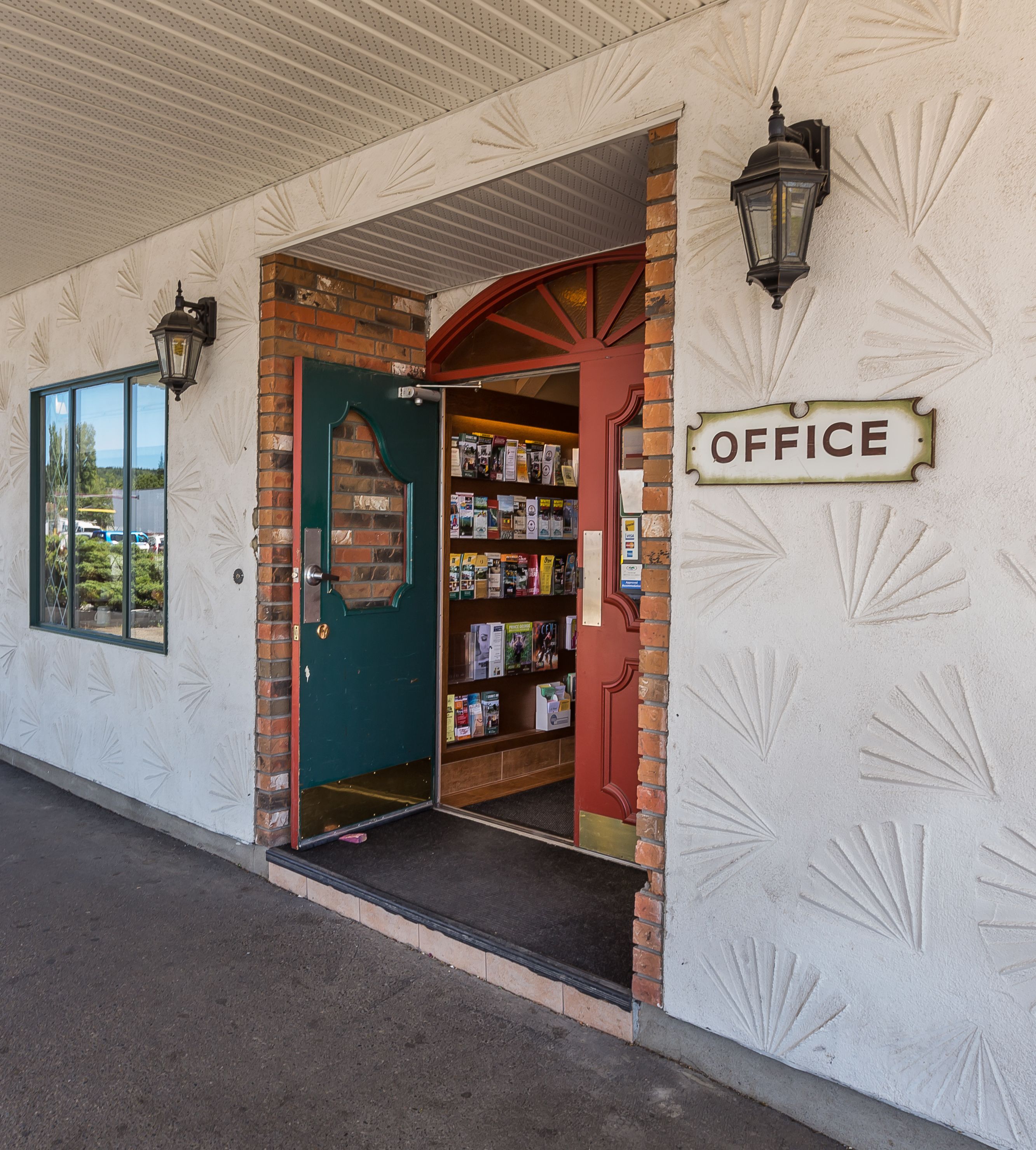 Une entrée d’immeuble avec une porte verte, une enseigne indiquant « BUREAU » et une bibliothèque remplie de livres.