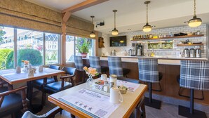 A restaurant with a bar area, wooden tables, and chairs. - Grama's Inn (Prince George)