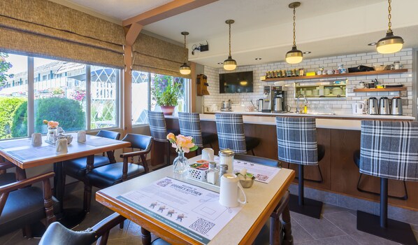 A restaurant with a bar area, wooden tables, and chairs. - Grama's Inn (Prince George)