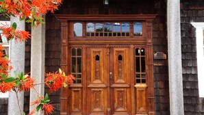 A wooden double door with intricate carvings and a small sign above it. - Hotel Boutique Casa Werner (Llanquihue)