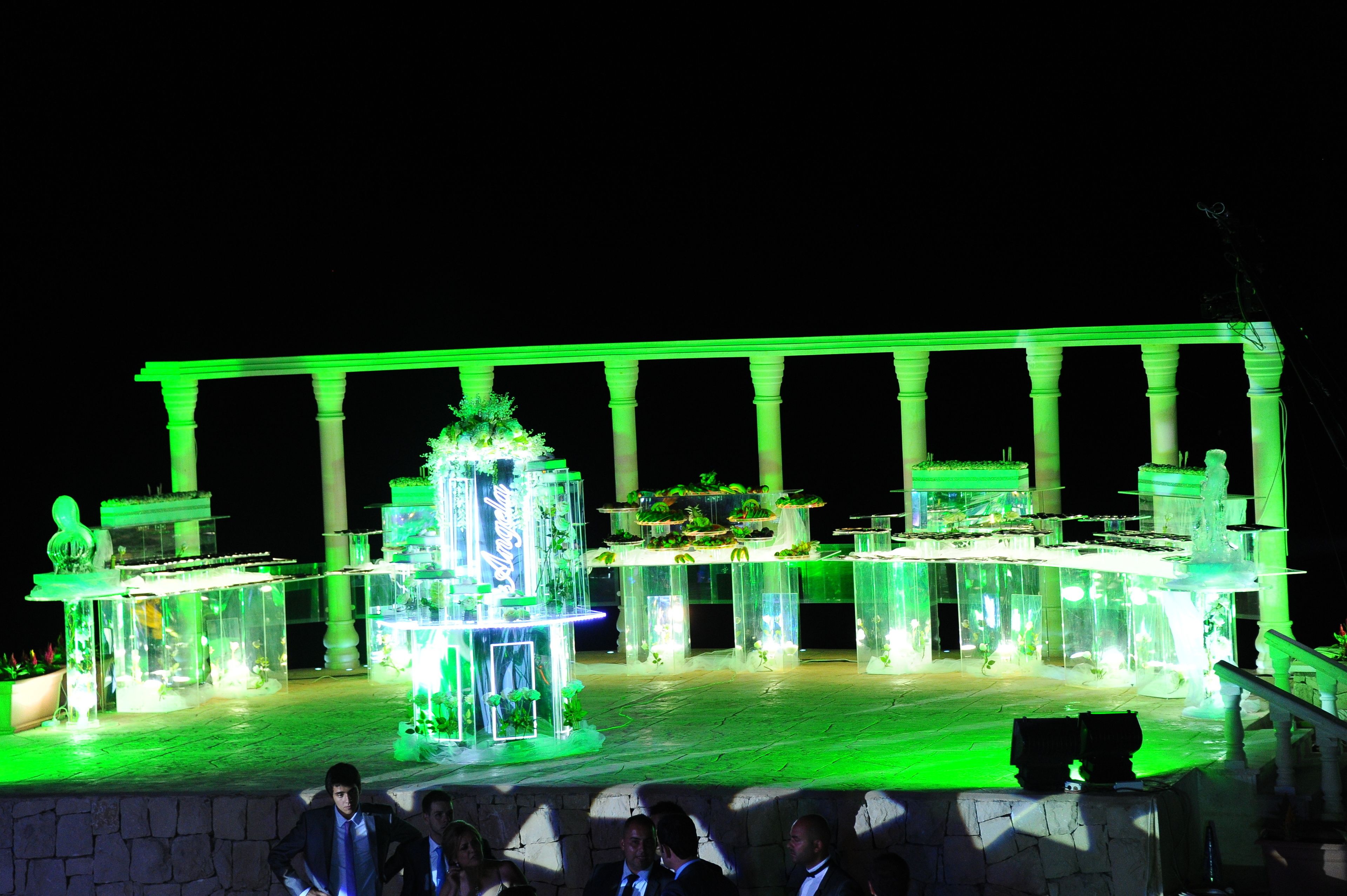 Um palco iluminado em verde, com uma fonte e colunas, provavelmente para um evento.