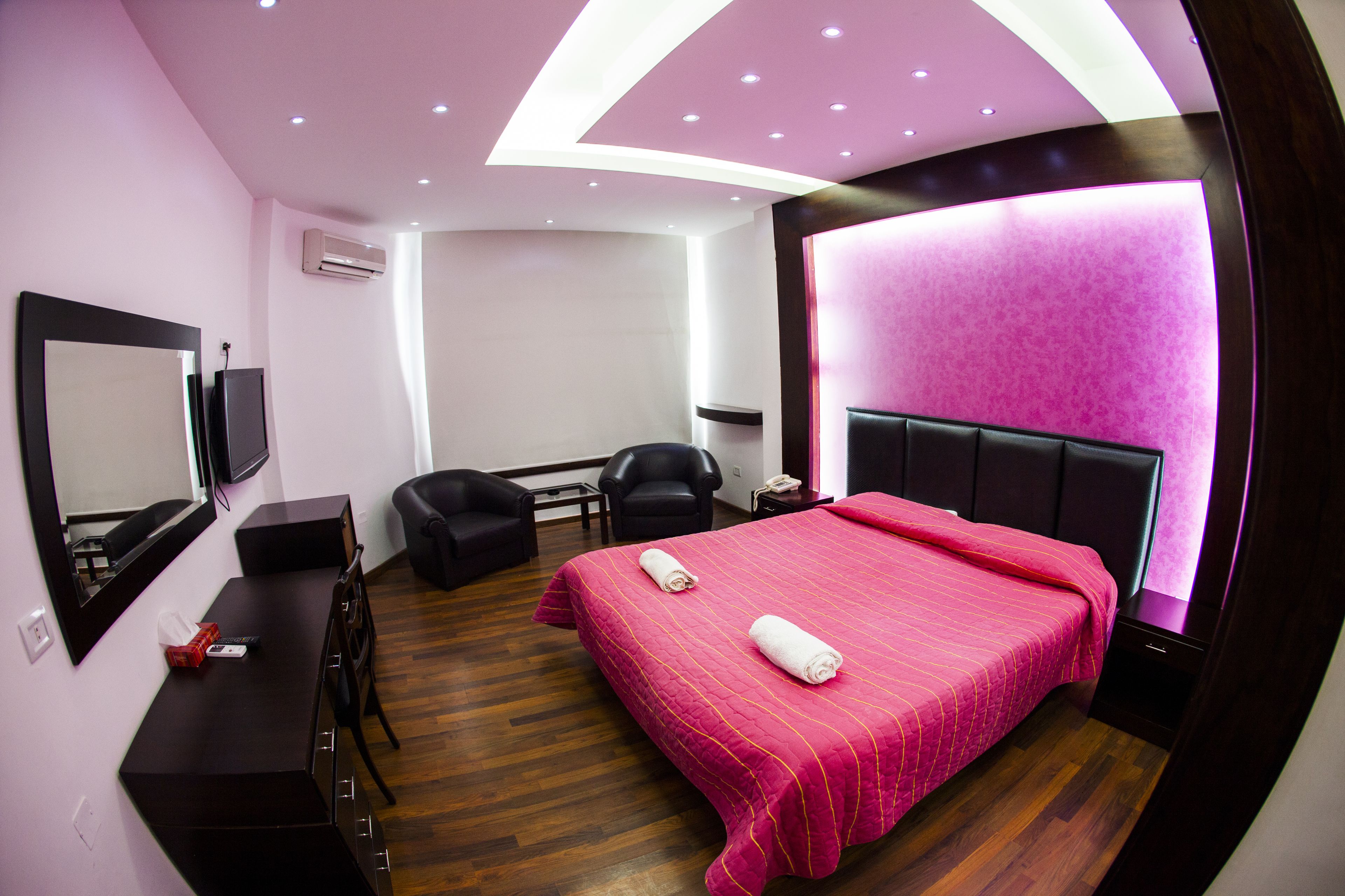 Una habitación de hotel moderna con una cama grande, un escritorio, una silla y un televisor.