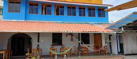 A two-story building with a swimming pool, outdoor seating, and a hammock.