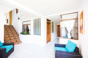 A spacious living area with a staircase, a glass door, and a large window.