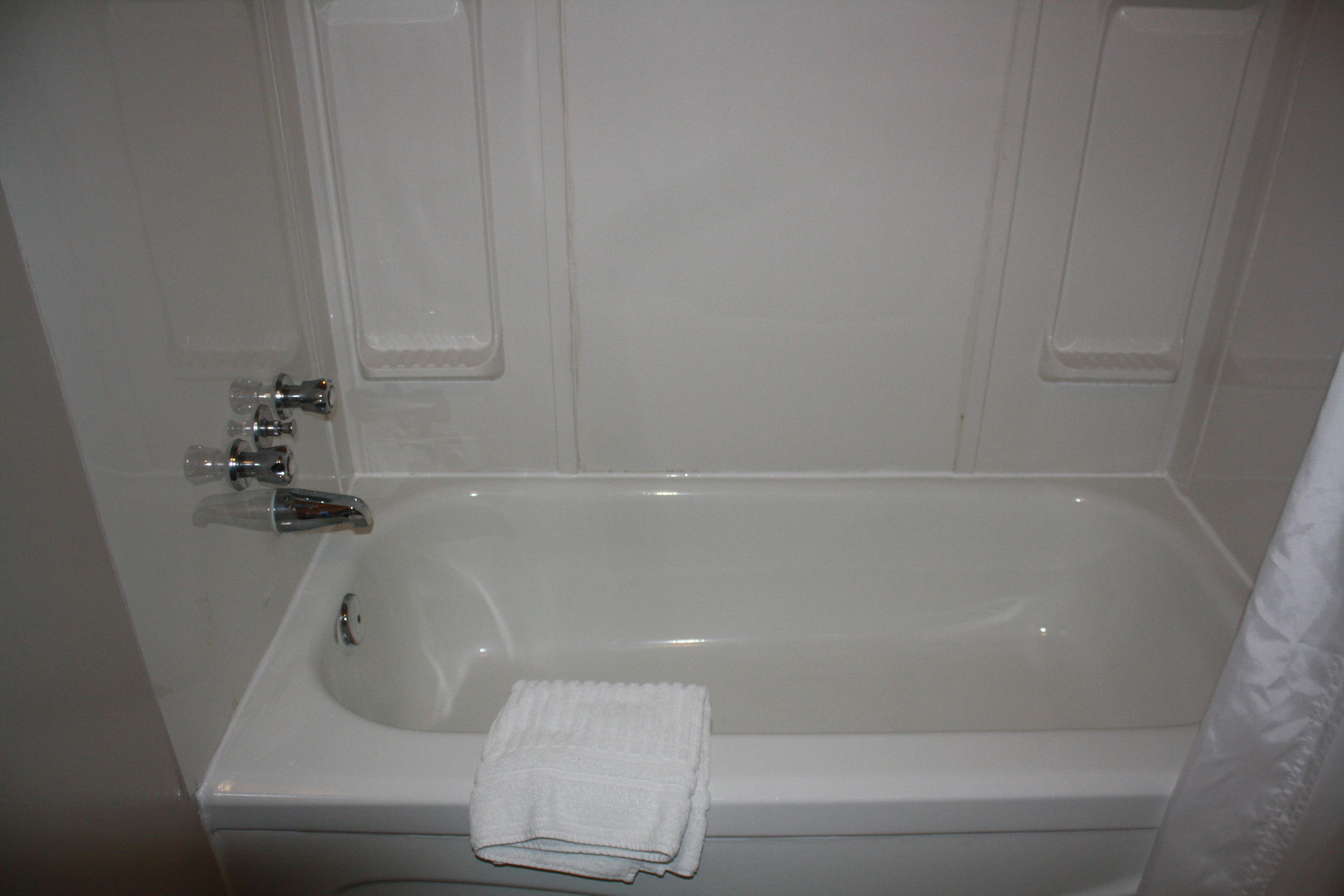 A white bathtub with a folded white towel.