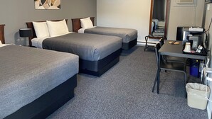A hotel room with two beds, a desk, a coffee maker, and a mirror. - Monashee Lodge (Revelstoke)