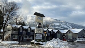 A motel with a sign indicating "Motel, Great Rooms, Great Rates" and a welcome sign. - Monashee Lodge (Revelstoke)