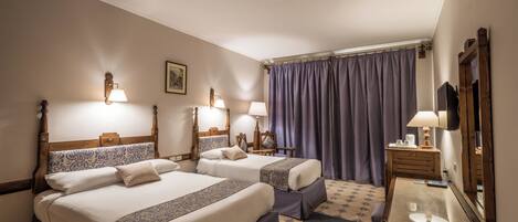 A hotel room with two beds, a desk, a chair, a mirror, and a window with curtains.
