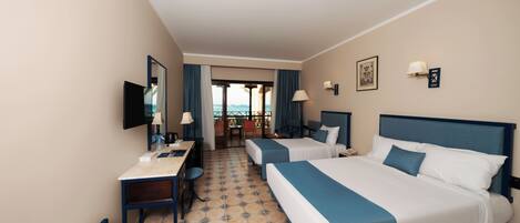 A hotel room with two beds, a desk, a chair, a TV, and a view of the outside.