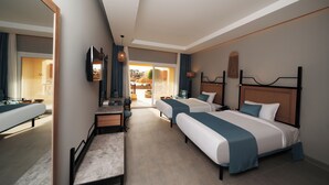 Habitación de hotel con dos camas, un escritorio, una silla, un televisor y vistas al exterior.