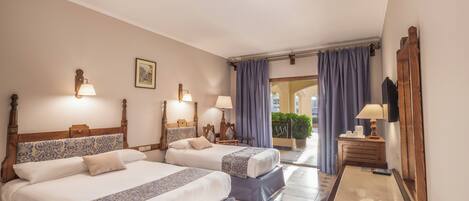 Habitación de hotel con dos camas, cabecera de madera, mesita de noche, espejo y vista al patio.