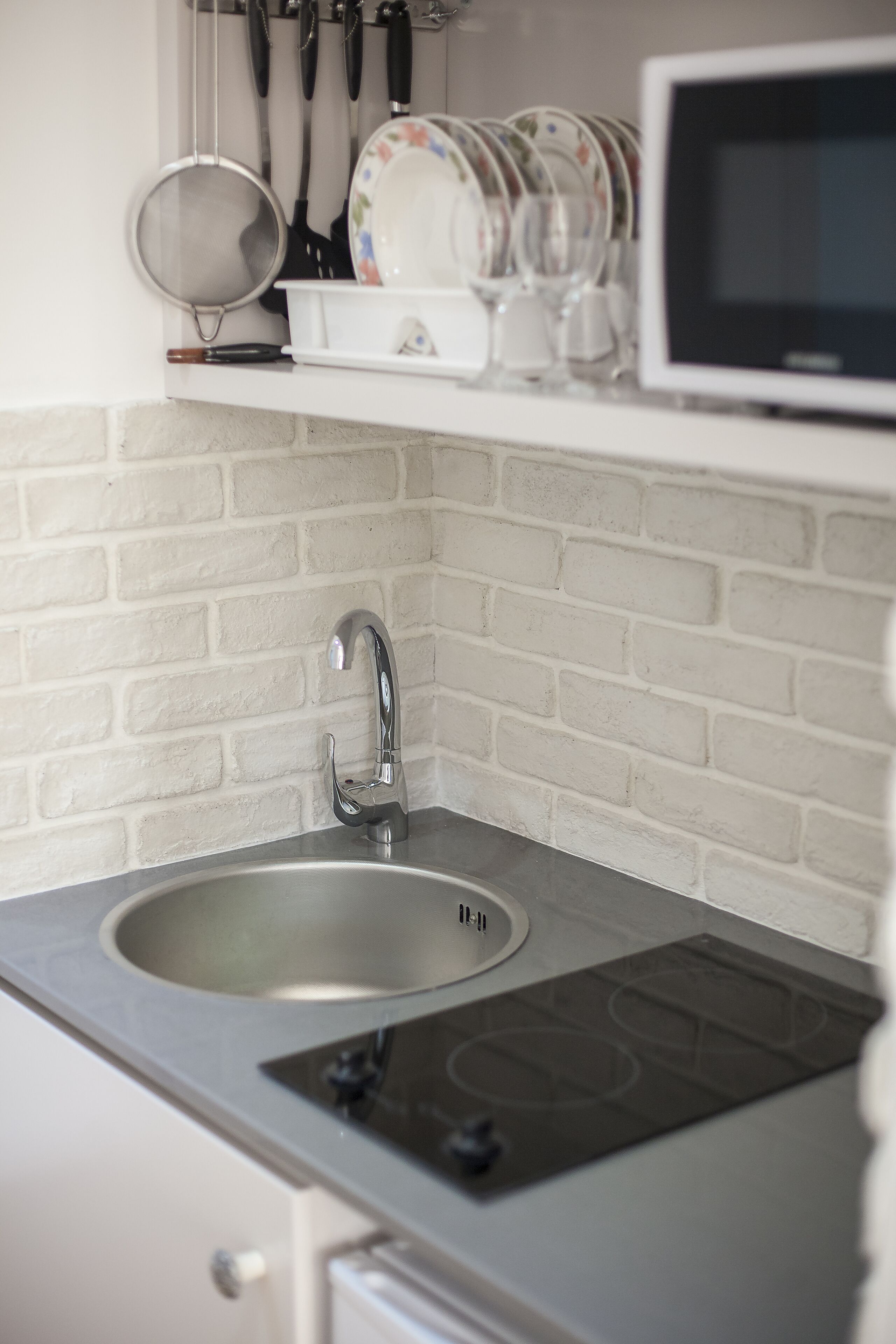 Una cocina con un lavamanos de acero inoxidable, un grifo moderno y una estufa empotrada.