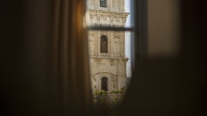 A view through a window of a historic building with arched windows and a bell tower. - Operetta House (Larnaca)