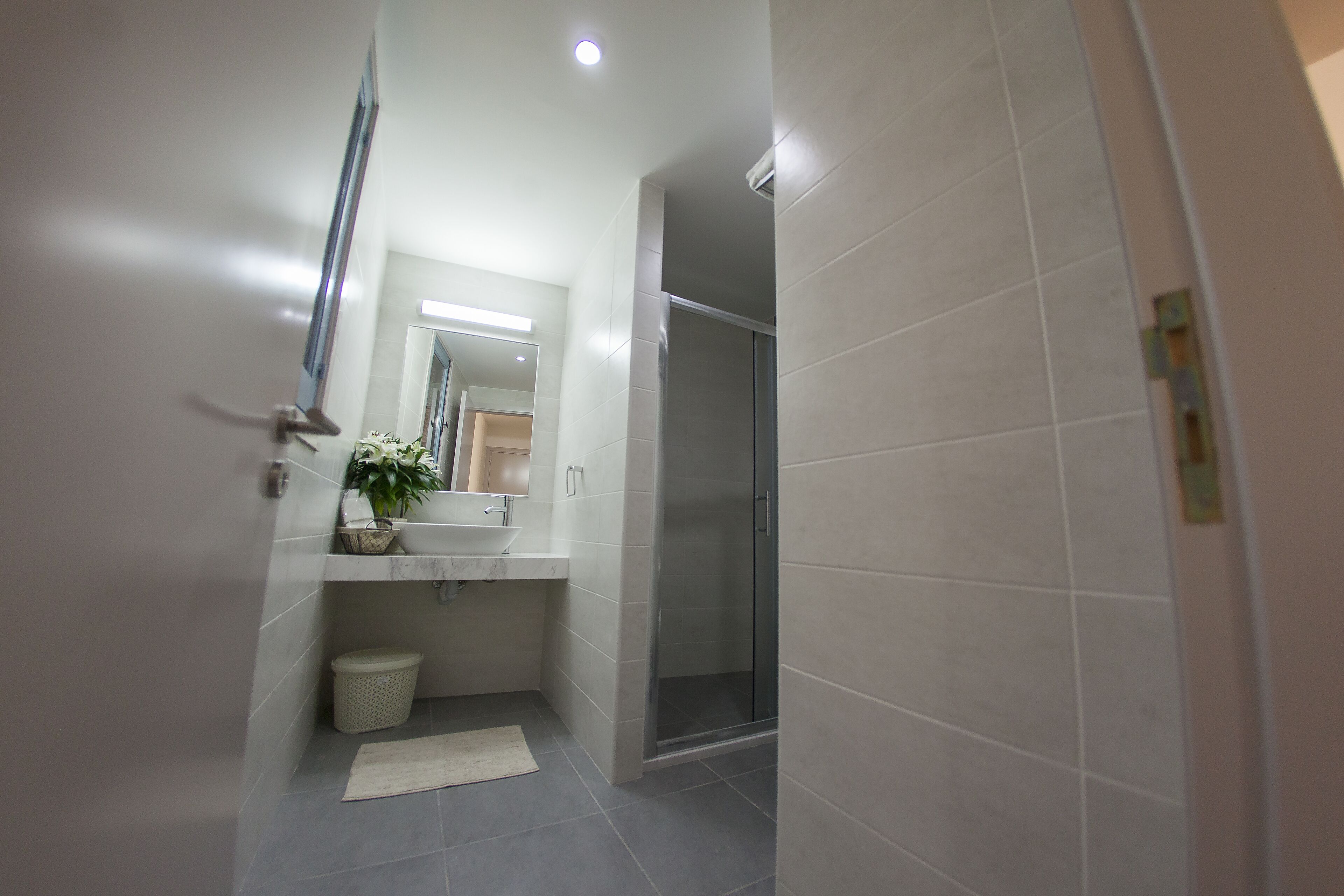 Un baño moderno con ducha, lavamanos y espejo.