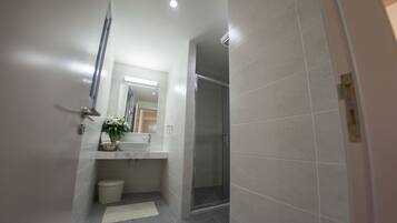 Un baño moderno con ducha, lavamanos y espejo.