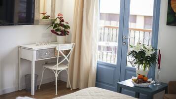 Una habitación con un escritorio blanco, una silla y una pequeña mesa con una planta y fruta.
