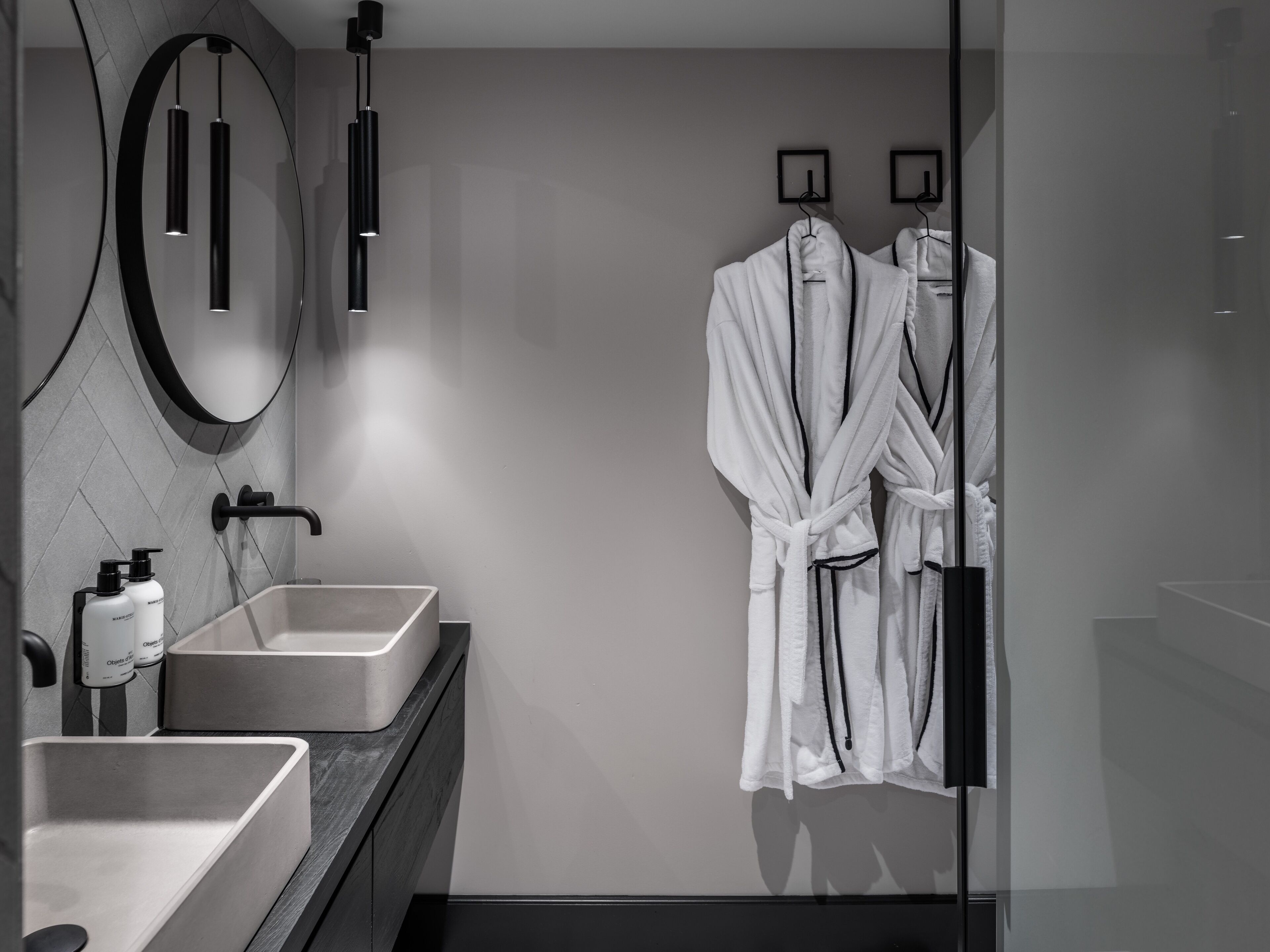 A modern bathroom with a large mirror, two sinks, and a glass shower enclosure.
