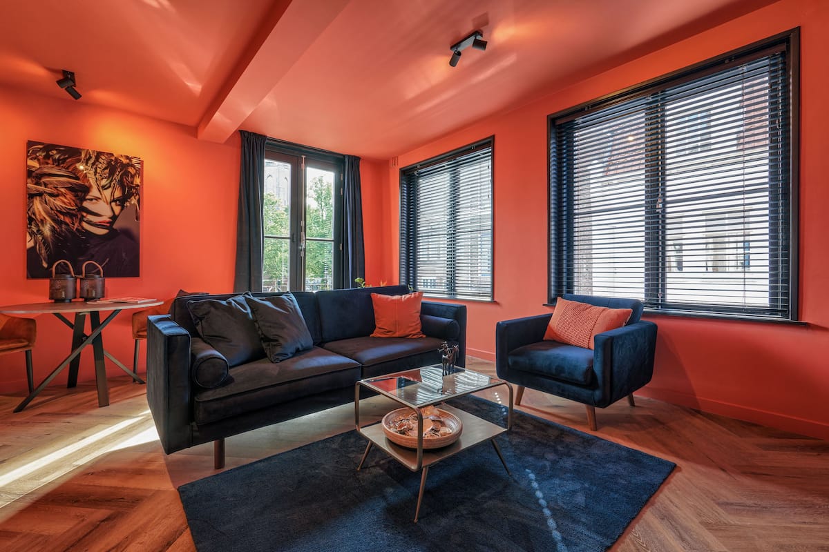 Un salon moderne avec un canapé noir, une table basse en verre et un fauteuil bleu.