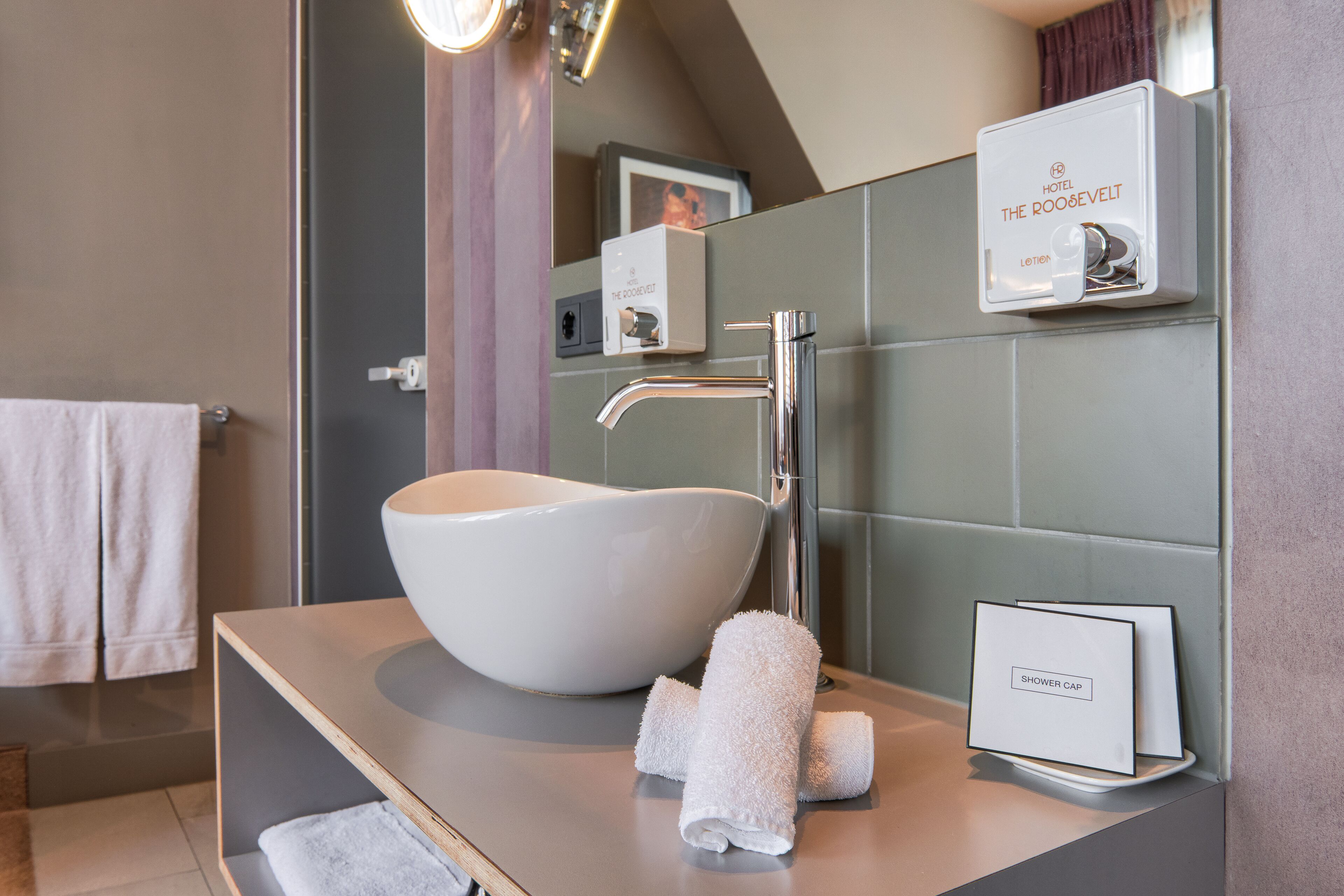 Ein modernes Badezimmer mit einem großen, weißen Waschtischbecken, einem Chrom-Wasserhahn und einem Handtuchhalter mit zwei Handtüchern.