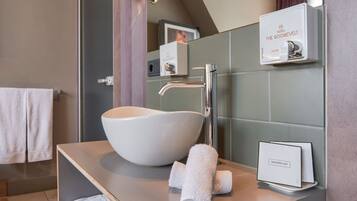 Ein modernes Badezimmer mit einem großen, weißen Waschtischbecken, einem Chrom-Wasserhahn und einem Handtuchhalter mit zwei Handtüchern.
