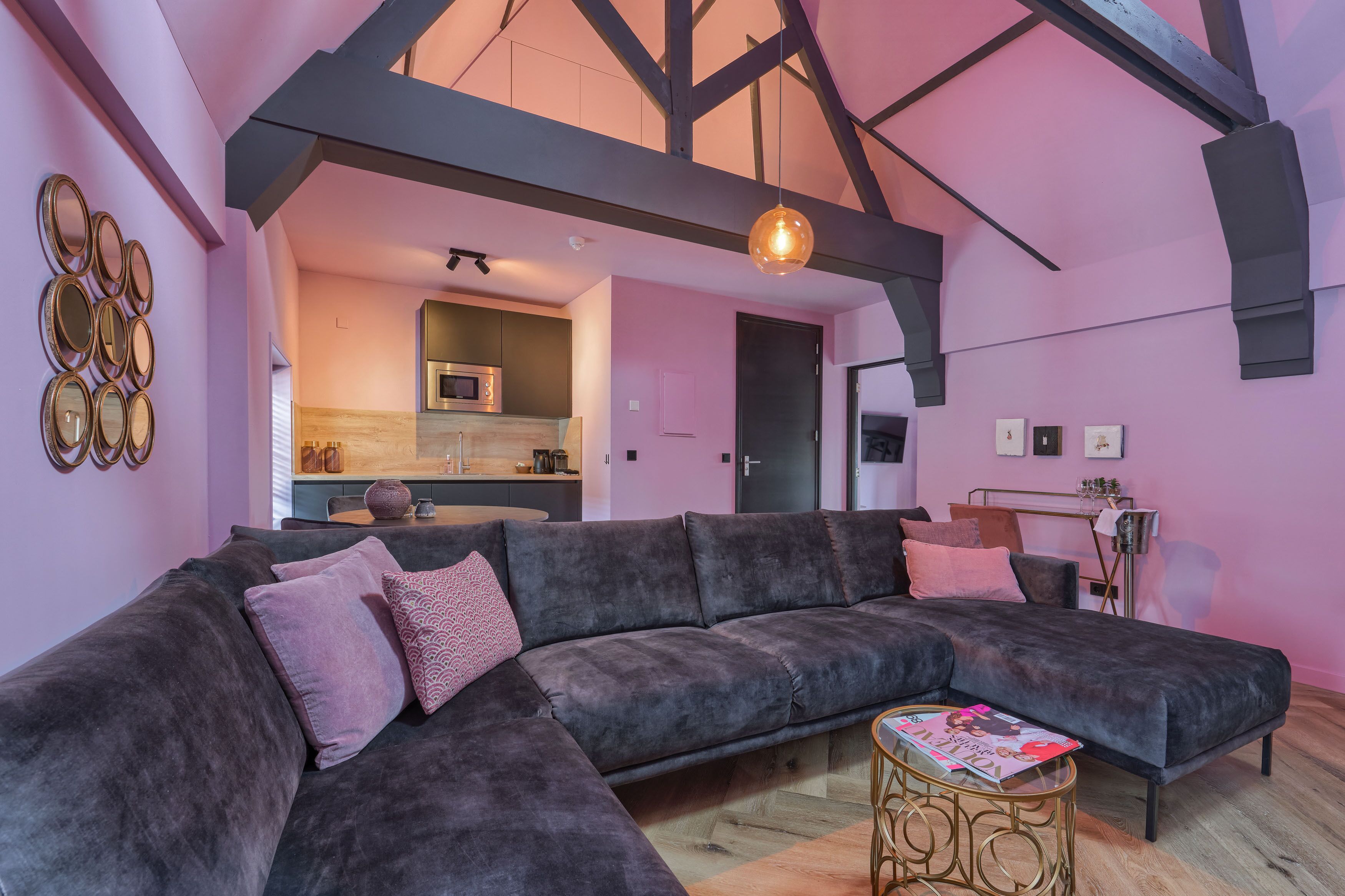 A modern living room with a large sectional sofa, a round coffee table, and a kitchen in the background.