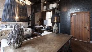 A modern interior with a wooden herringbone floor, a large metallic sculpture, a staircase, and a wooden door. - Boutique Hotel The Roosevelt (Middelburg)