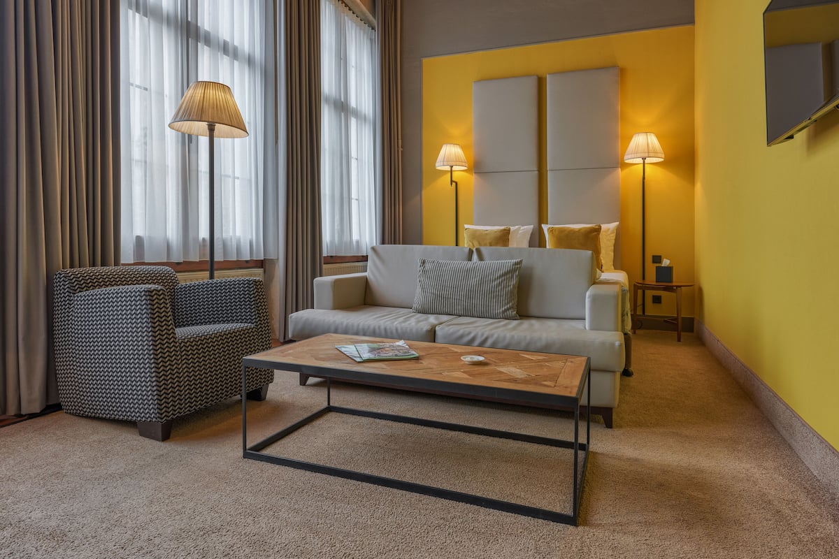 Un salon moderne avec un canapé, un fauteuil et une table basse. Deux lampes sont placées de part et d’autre du canapé.