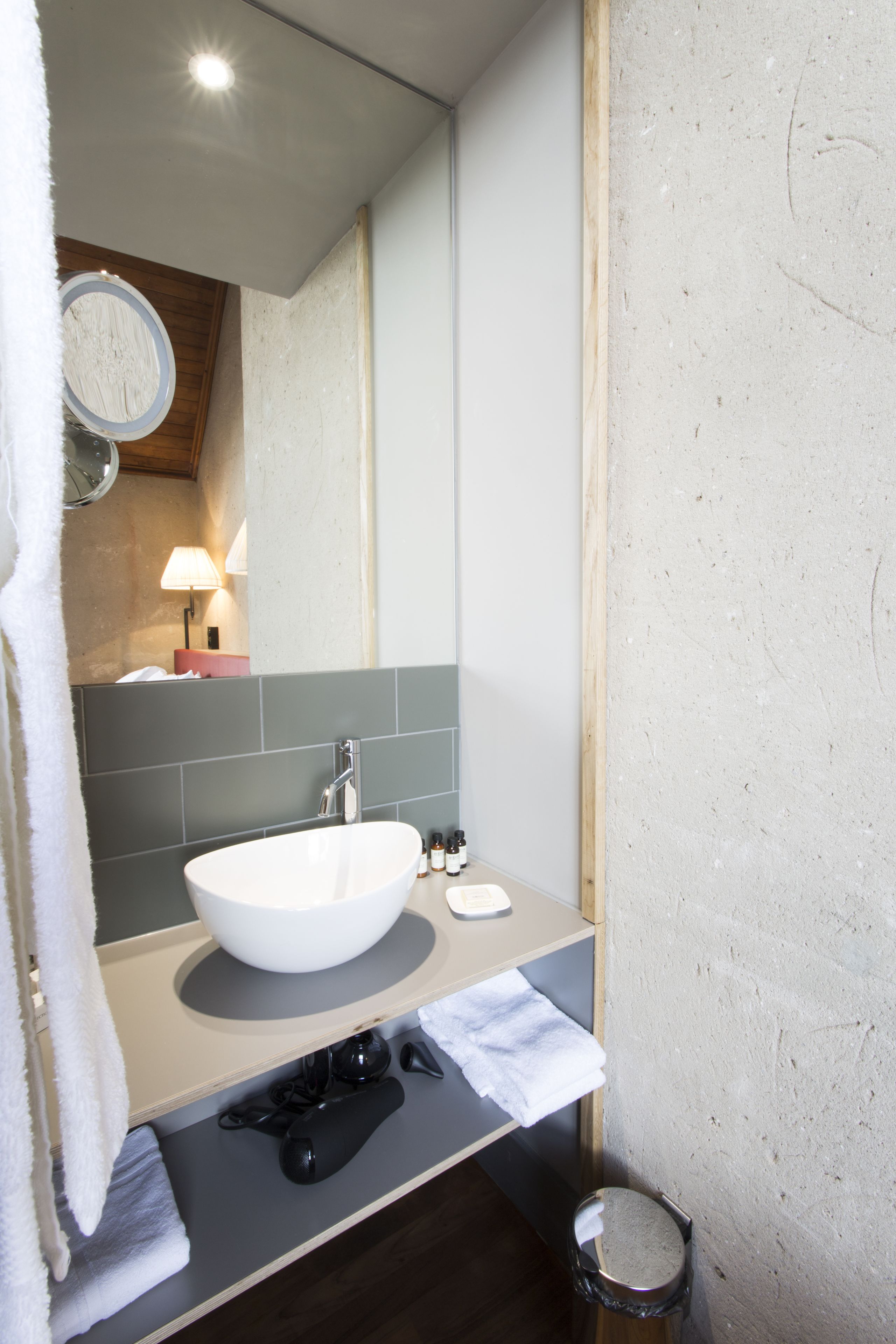 Un baño con lavamanos blanco, un espejo, toallero y un cubo de basura.