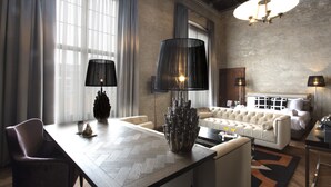 A modern hotel room with a large bed, a sofa, a dining table, and a chandelier. - Boutique Hotel The Roosevelt (Middelburg)